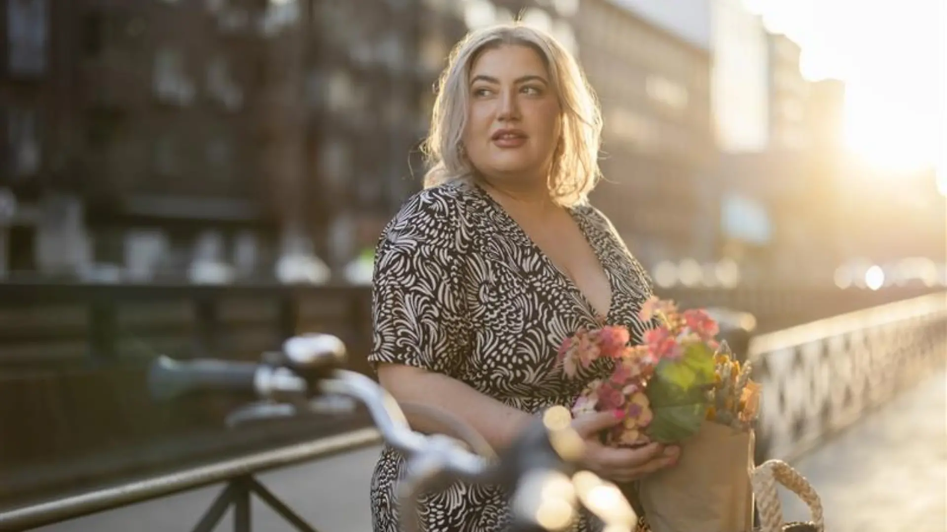 Blonde Frau steht vor einem Fahrrad.