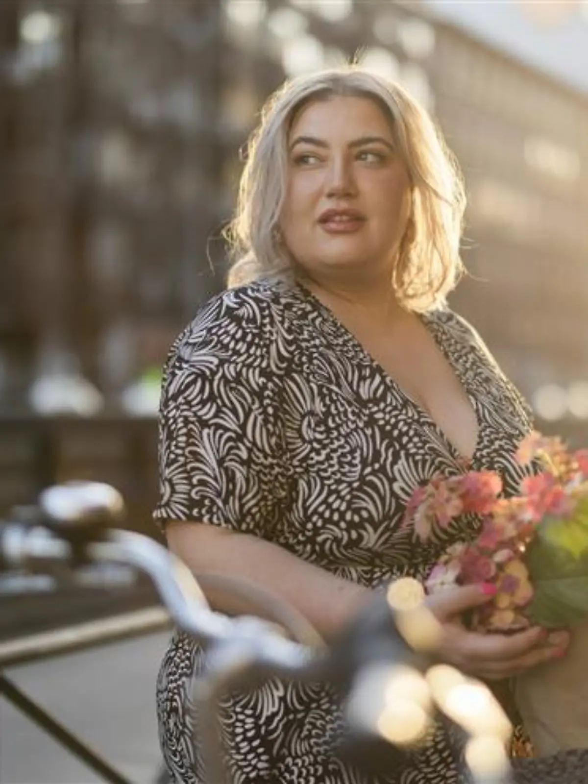 Blonde Frau steht vor einem Fahrrad.