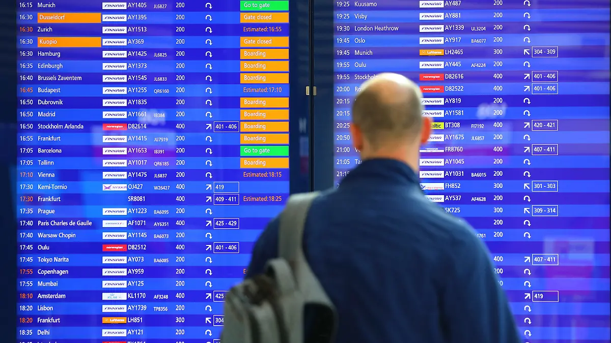 Ein Mann steht vor einer Abflugtafel am Flughafen