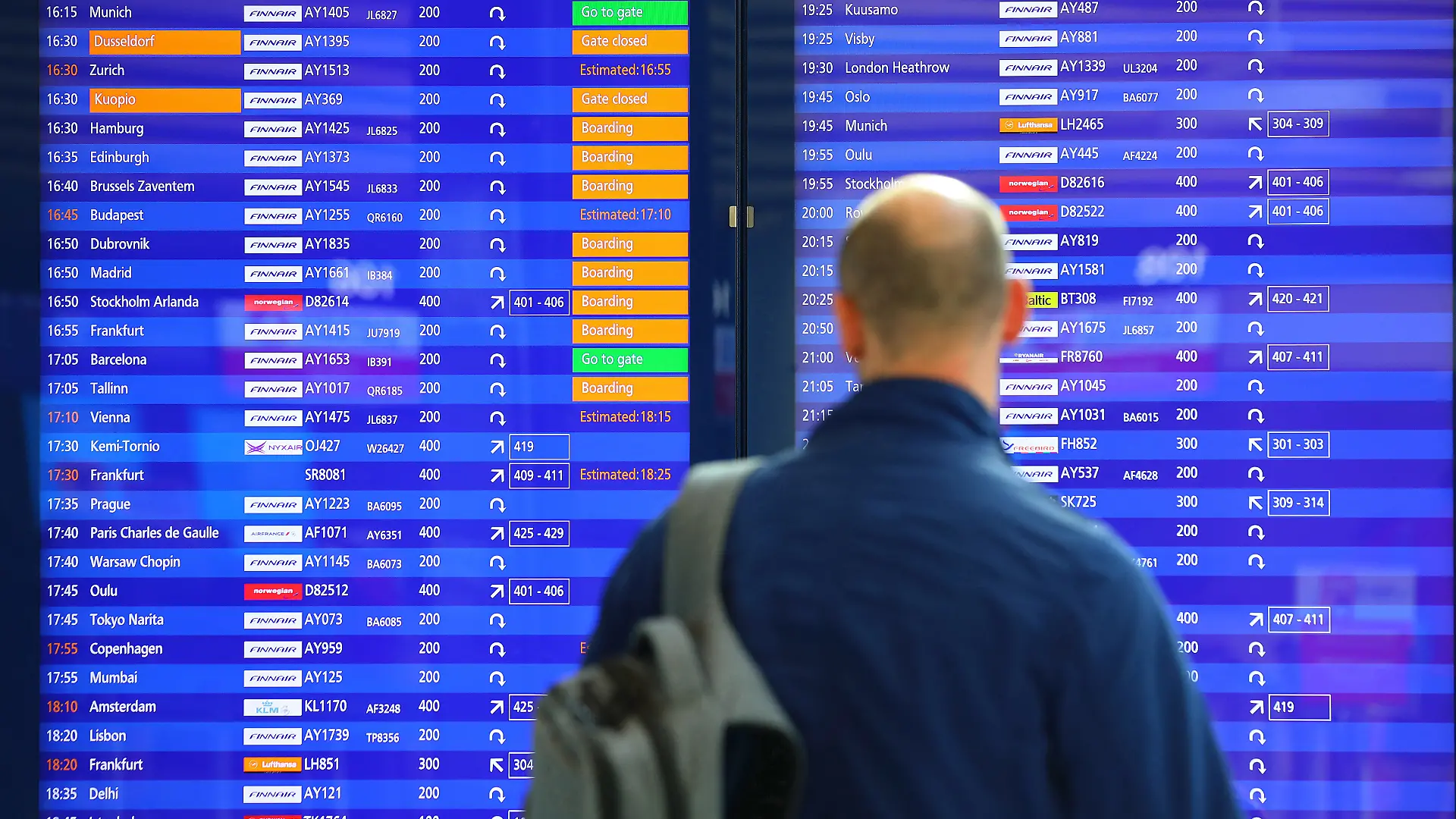 Ein Mann steht vor einer Abflugtafel am Flughafen