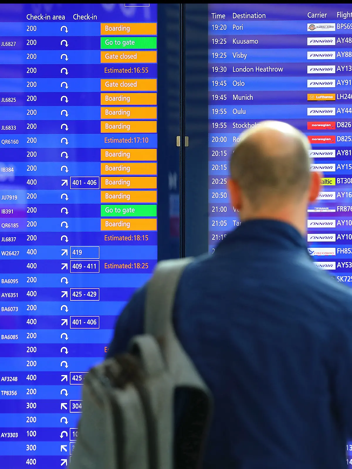 Ein Mann steht vor einer Abflugtafel am Flughafen