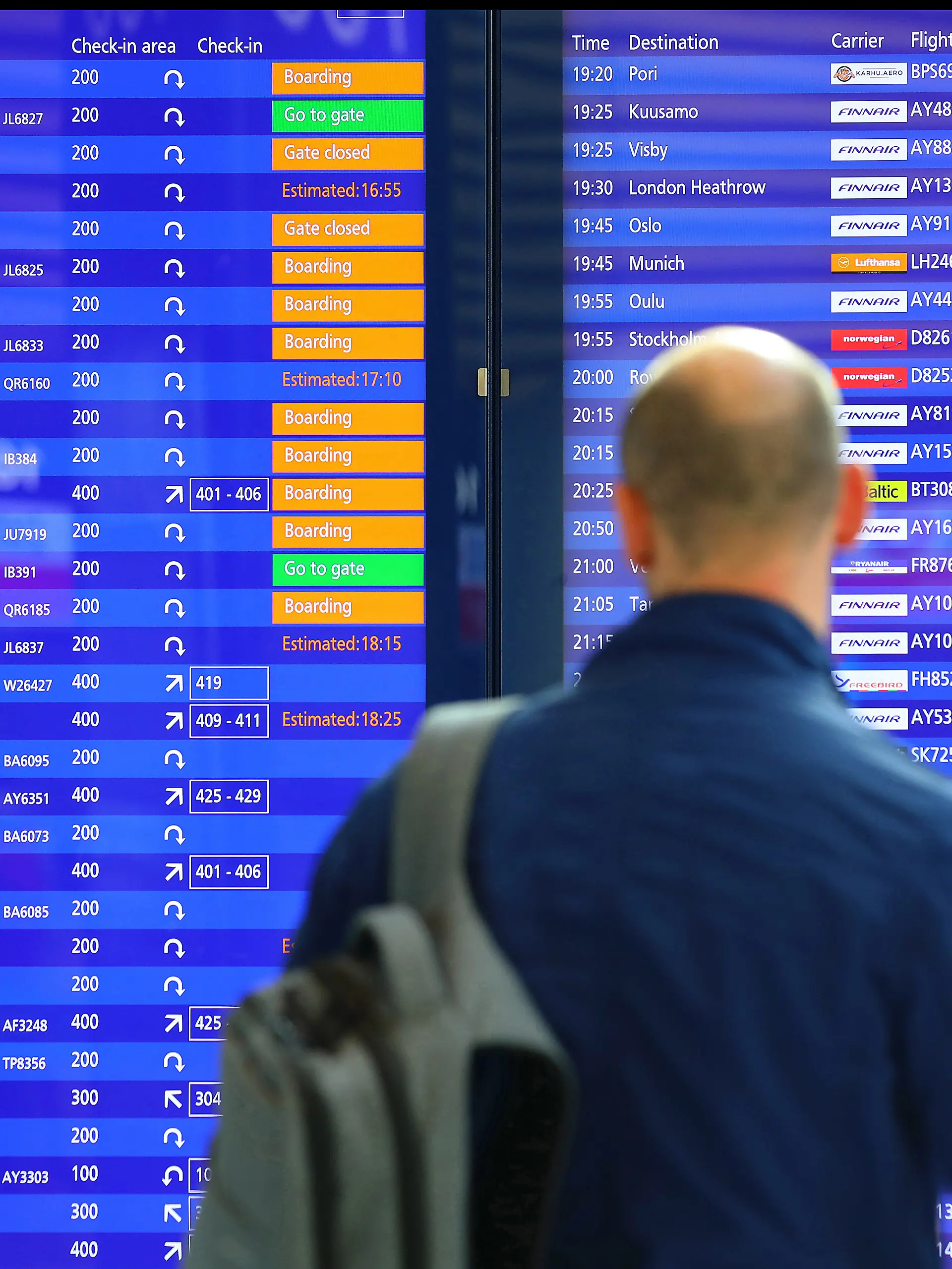 Ein Mann steht vor einer Abflugtafel am Flughafen