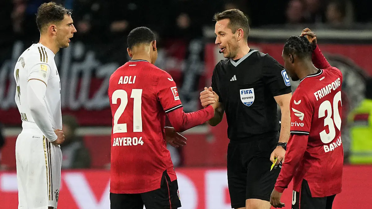 Referee Tobias Stieler shakes hands with Leverkusen's Amine Adli, after he took back a yellow card and decided penalty for Leverkusen instead for the second time after contact with the video referee during the German Bundesliga soccer match between Bayer Leverkusen and Bayern Munich in Leverkusen, Germany, Sunday, March 19, 2023. The referee (AP Photo/Martin Meissner)
