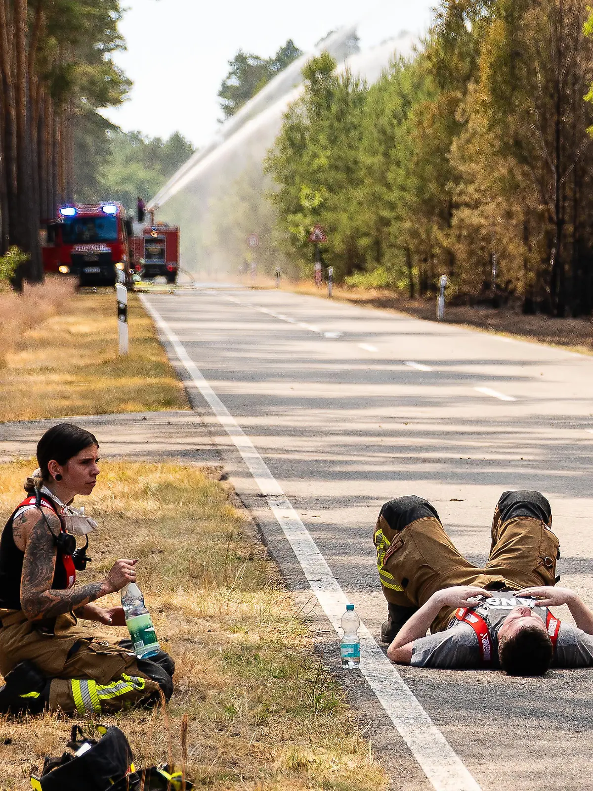 Feuerwehrleute erholen sich einen Moment am Straßenrand
