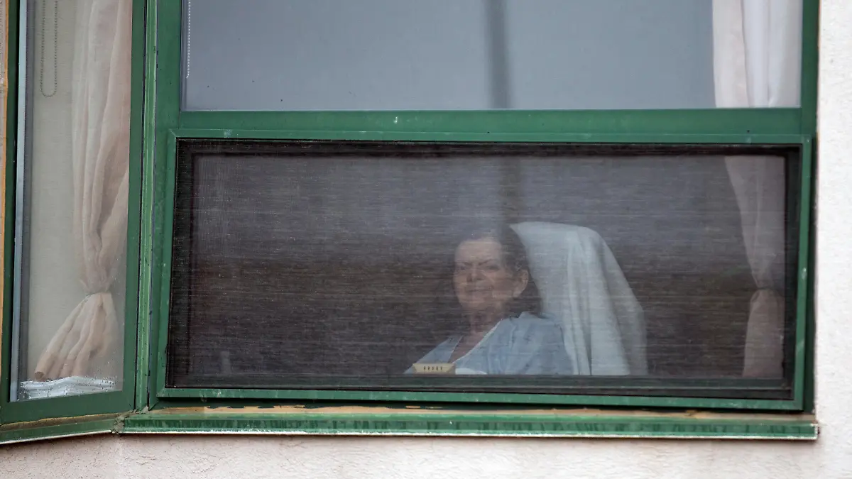 A resident looks out her window at Residence Herron, a senior's long-term care facility, following a number of deaths since the coronavirus disease (COVID-19) outbreak, in the suburb of Dorval in Montreal Quebec, Canada April 13, 2020. REUTERS/Christinne Muschi