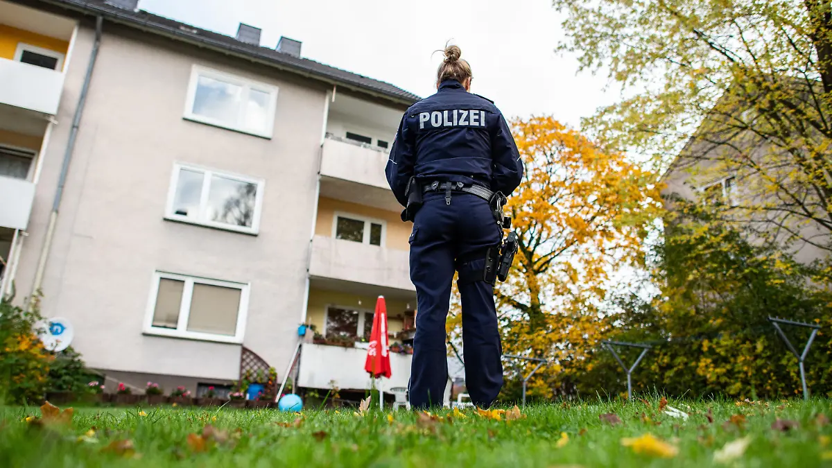 ARCHIV - 07.11.2019, Nordrhein-Westfalen, Detmold: Eine Polizistin steht im Garten des Mehrfamilienhauses, in dem eine 15-Jährige ihren dreijährigen Halbbruder getötet haben soll. Fünf Monate, nachdem eine Jugendliche ihren erst drei Jahre alten Halbbruder durch 28 Messerstiche getötet haben soll, beginnt am Montag am Landgericht Detmold der Prozess gegen das Mädchen. Unter Ausschluss der Öffentlichkeit muss sich die 15-Jährige wegen Mordes verantworten. (Zu dpa «Kleinkind (3) erstochen: Jugendliche Halbschwester vor Gericht») Foto: Guido Kirchner/dpa +++ dpa-Bildfunk +++