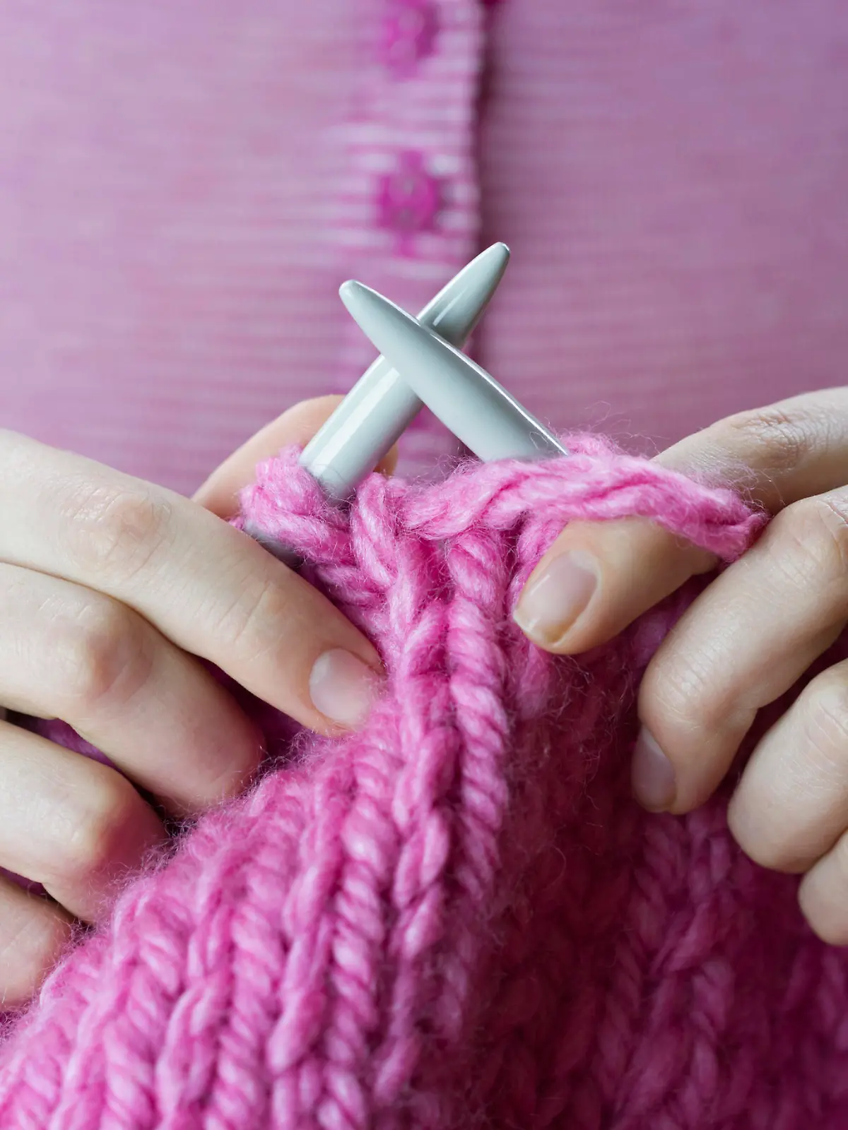 Close up of a female hands knitting pink woolen threads
