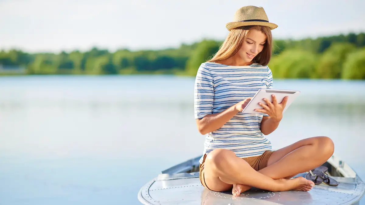Shot of a young woman using a digital tablet on boat at the lake