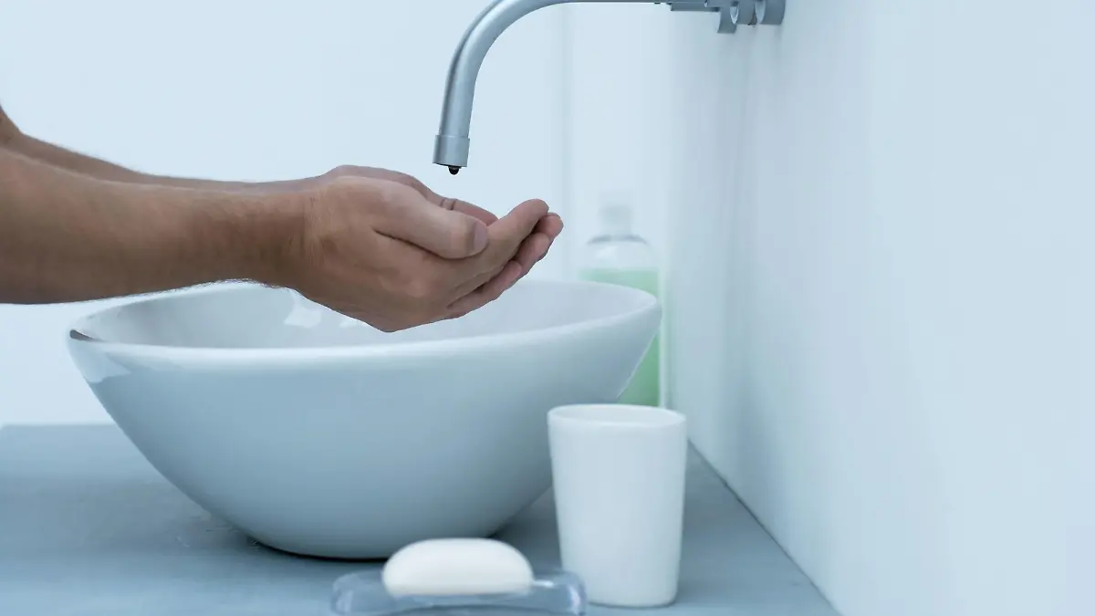 Man holding hands under dripping faucet in bathroom sink, cropped PUBLICATIONxINxGERxSUIxAUTxONLY Copyright: SannaxLindberg 35778585st