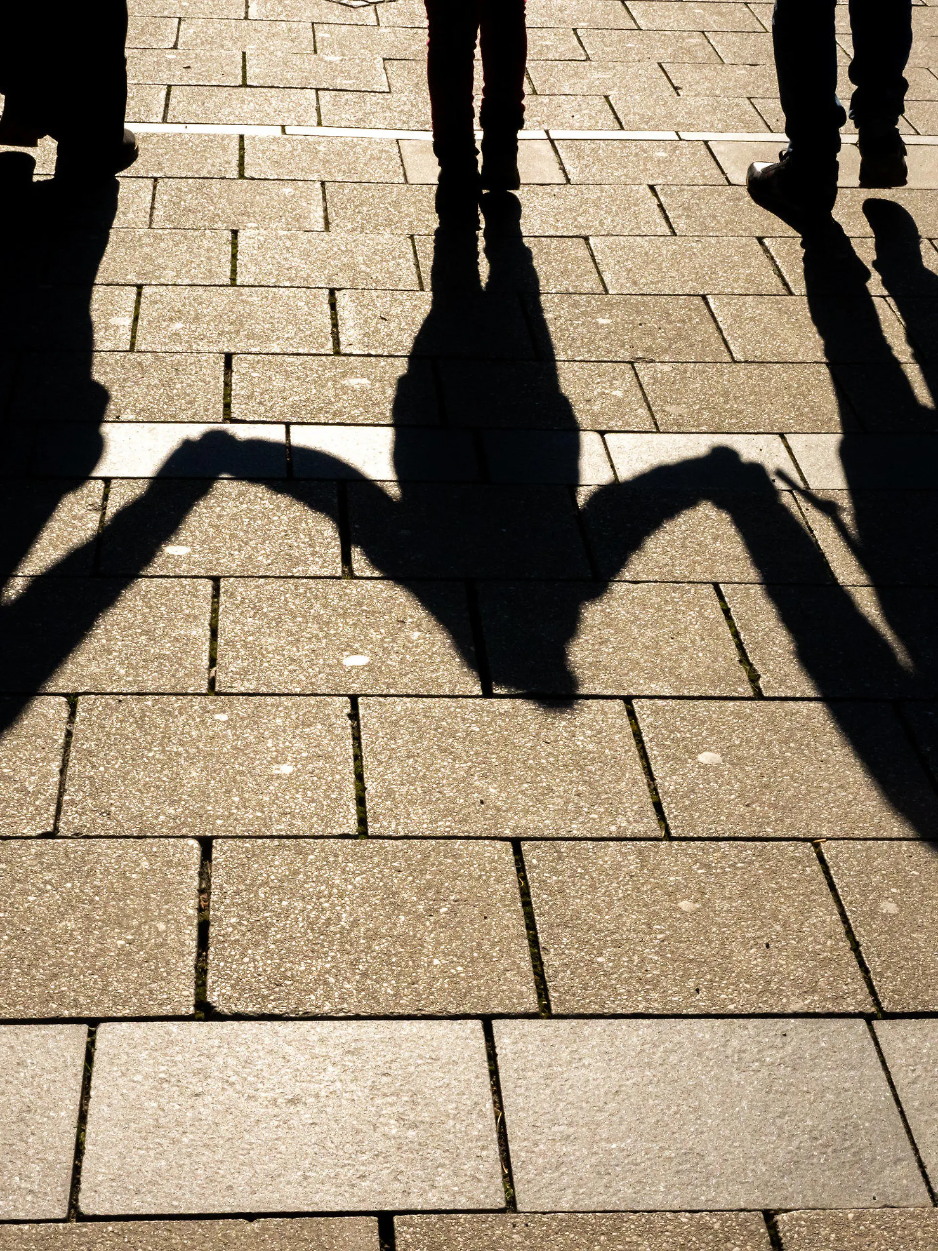ARCHIV - 04.04.2022, Bayern, München: ILLUSTRATION - Die Schatten von zwei Erwachsenen und einem Kind fallen in den Morgenstunden auf den Asphalt. (zu dpa: «Streit um Kindergrundsicherung: Paus will Kinderfreibeträge senken») Foto: Peter Kneffel/dpa +++ dpa-Bildfunk +++