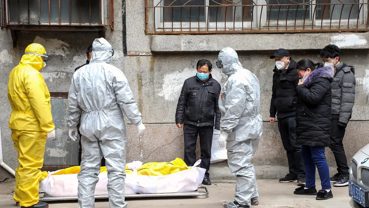 FILE - In this Feb. 1, 2020, file photo, funeral home workers remove the body of a person suspected to have died from the coronavirus outbreak from a residential building in Wuhan in central China's Hubei Province. The central Chinese city of Wuhan has raised its number of COVID-19 fatalities by more than 1,000. State media said the undercount had been due to the insufficient admission capabilities at overwhelmed medical facilities at the peak of the outbreak. (Chinatopix via AP, File)
