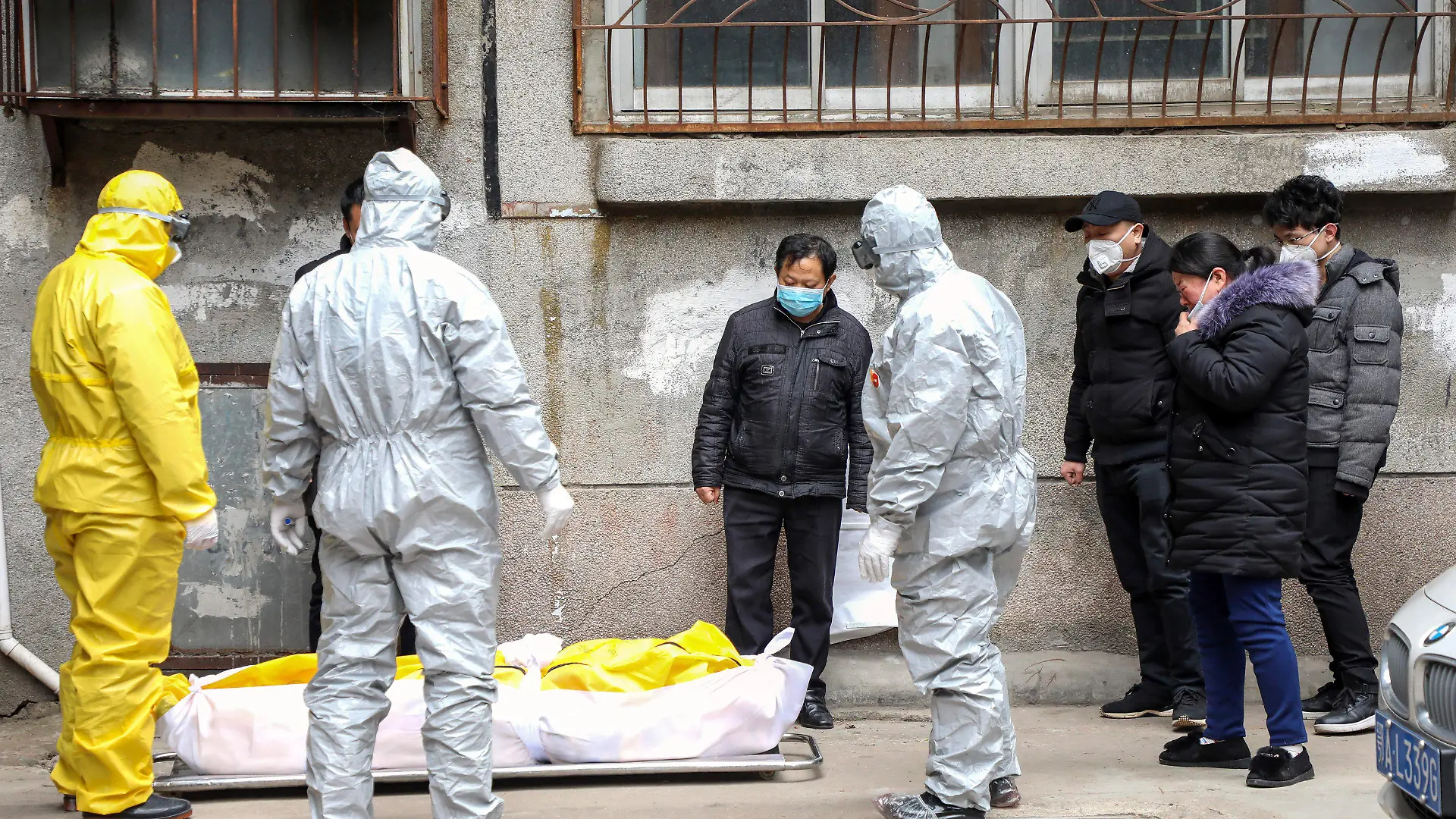 FILE - In this Feb. 1, 2020, file photo, funeral home workers remove the body of a person suspected to have died from the coronavirus outbreak from a residential building in Wuhan in central China's Hubei Province. The central Chinese city of Wuhan has raised its number of COVID-19 fatalities by more than 1,000. State media said the undercount had been due to the insufficient admission capabilities at overwhelmed medical facilities at the peak of the outbreak. (Chinatopix via AP, File)
