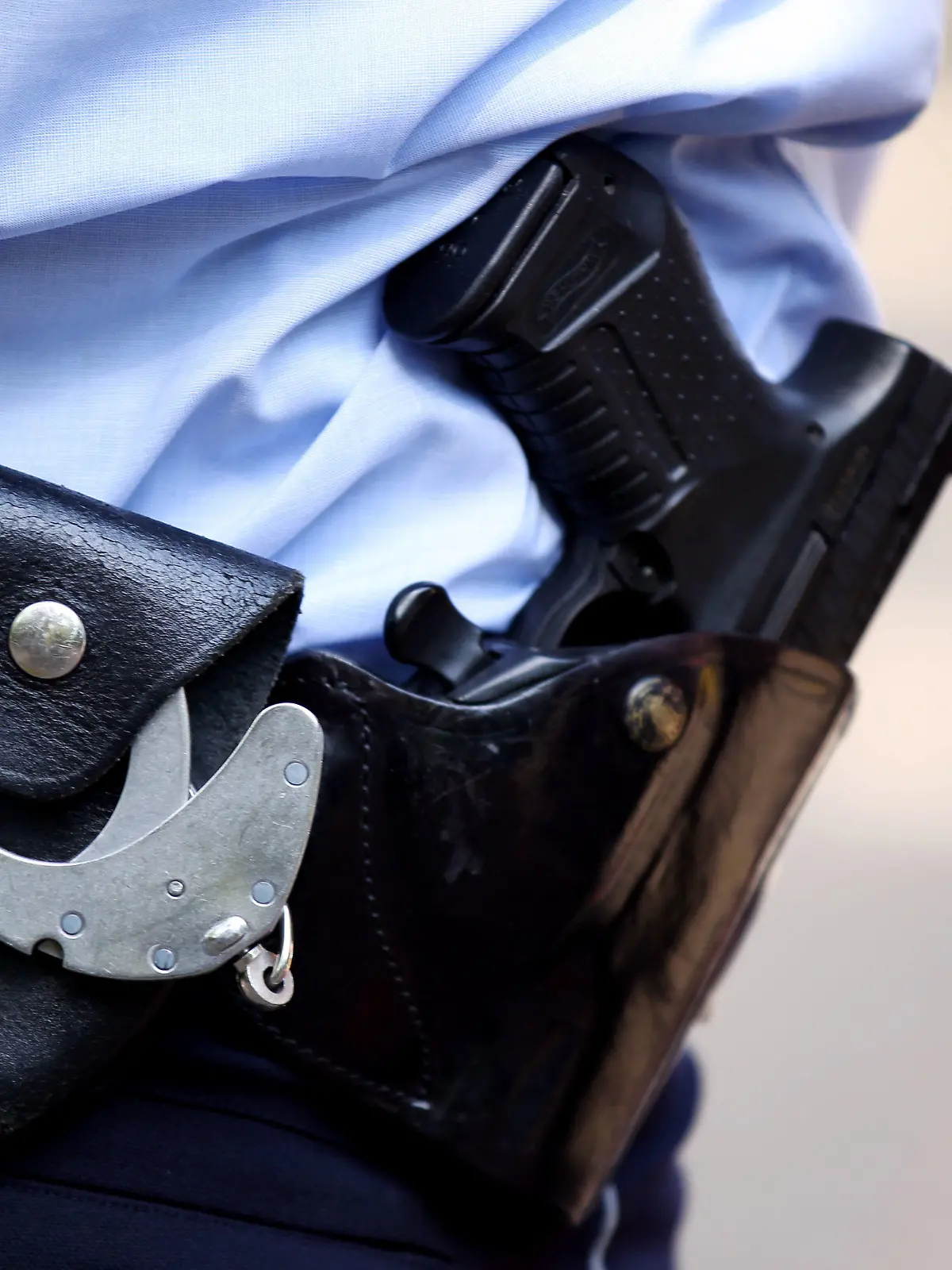 ARCHIV - 28.06.2011, Nordrhein-Westfalen, Köln: Ein Polizist trägt Handschellen und seine Dienstwaffe bei sich. Im Jahr 2022 sind in Sachsen zwei Menschen nach Schüssen aus Polizeiwaffen ums Leben gekommen. (zu dpa «Zwei Menschen 2022 nach Schusswaffeneinsatz der Polizei gestorben») Foto: Oliver Berg/dpa/Symbolbild +++ dpa-Bildfunk +++