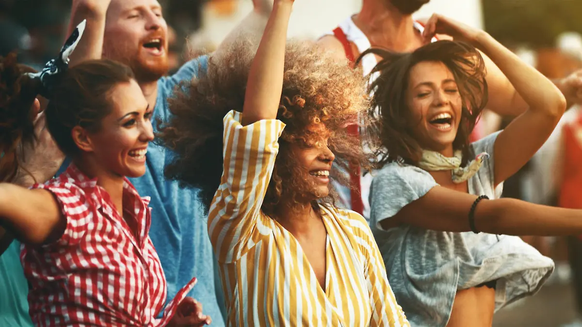 Closeup side view of group of group young adults having fun at a concert on a summer afternoon.