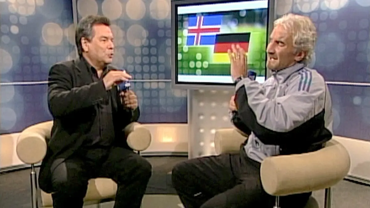 ARCHIV - 07.09.2003, Berlin: Das vom Video abgenommene Bild zeigt den damaligen Teamchef der deutschen Fußball-Nationalmannschaft, Rudi Völler, am 06.09.2003 in Reykjavik bei einem Interview im ARD-Studio im Gespräch mit Moderator Waldemar Hartmann. Nach dem 0:0 in der EM-Qualifikation gegen Island rastet der Teamchef vor laufender Kamera regelrecht aus. Hartmann haute er bei seiner Wutrede seinerzeit einen unvergesslichen Satz um die Ohren: «Du sitzt hier locker bequem auf deinem Stuhl, hast drei Weizenbier getrunken und bist schön locker.» (Bestmögliche Qualität) Foto: Ard/Ndr/ARD/NDR/dpa +++ dpa-Bildfunk +++