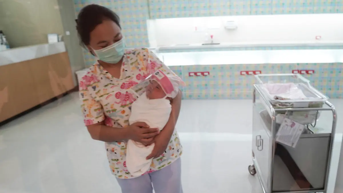A nurse wearing a protective face mask holds a newborn baby wearing a protective face shield during the coronavirus disease (COVID-19) outbreak at the Praram 9 hospital in Bangkok, Thailand, April 9, 2020. REUTERS/Athit Perawongmetha  