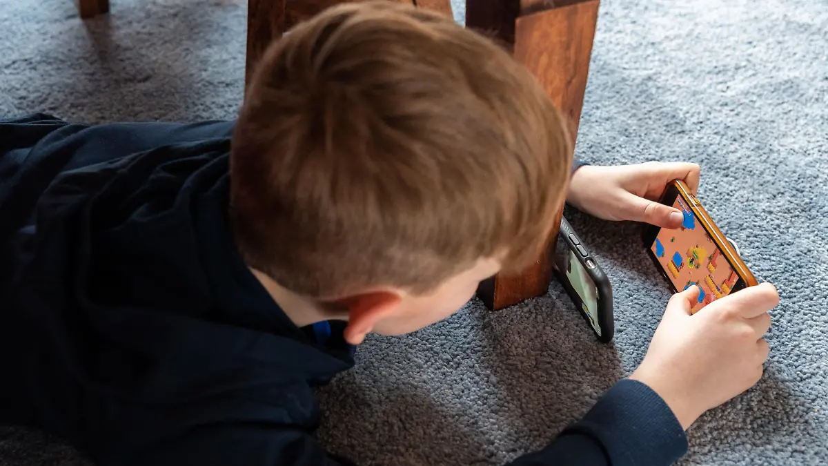ARCHIV - 20.03.2020, Sachsen, Dresden: Ein Junge spielt ein Videospiel auf seinem Smartphone und überträgt es mit einem zweiten Handy per Facetime zu seinem Freund. (zu dpa "Macht das Smartphone krank? - Eltern in Sorge um ihre Kinder") Foto: Robert Michael/dpa-Zentralbild/dpa +++ dpa-Bildfunk +++