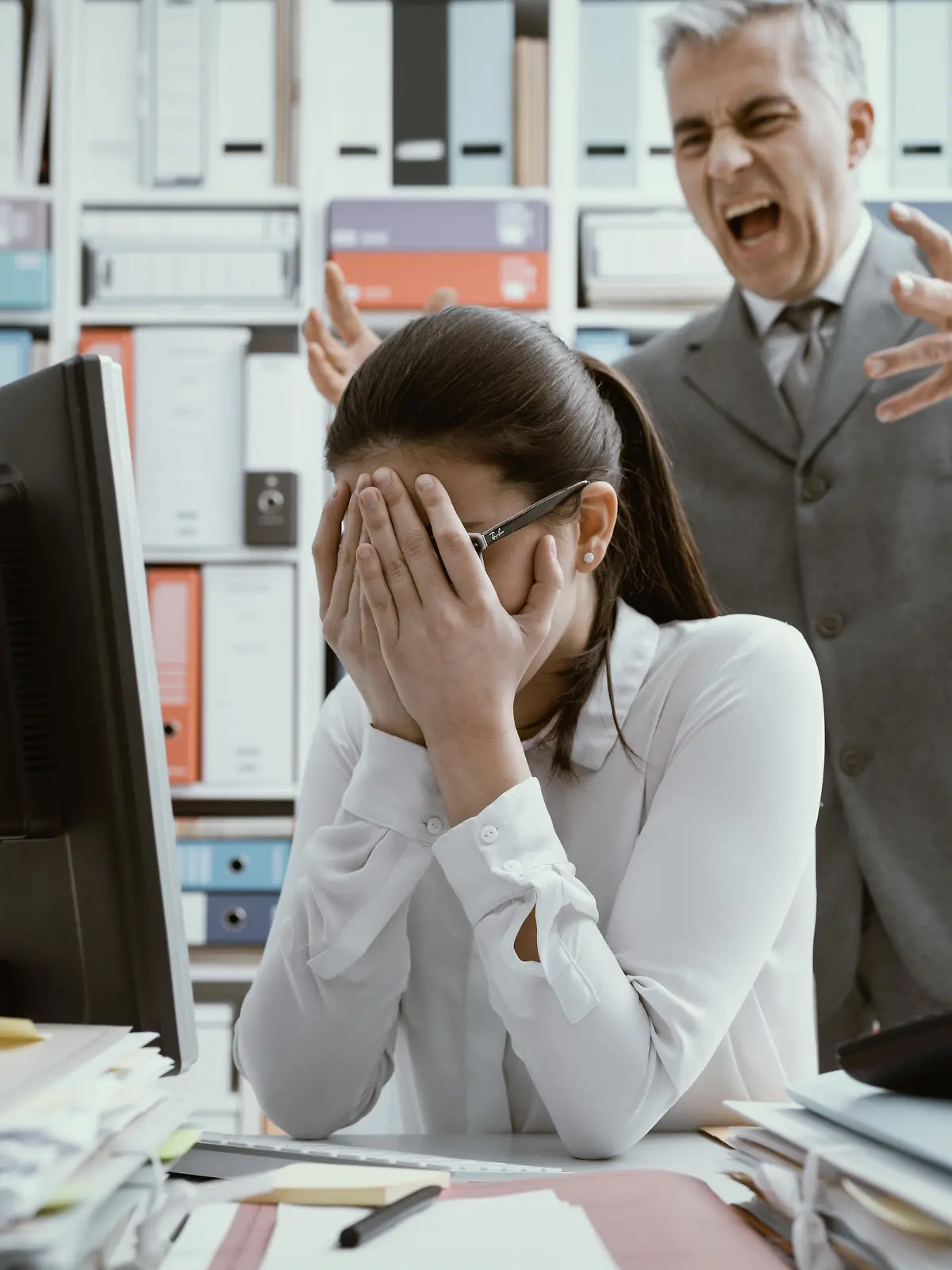 Angry boss yelling at his young employee, she is stressed and feeling frustrated: bullying boss and mobbing concept