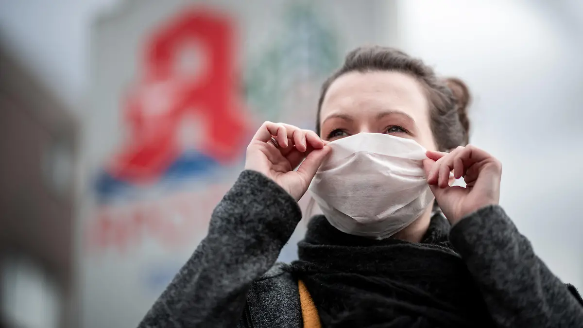 28.01.2020, Nordrhein-Westfalen, Oberhausen: Eine Frau trägt vor einer Apotheke eine Mund- und Nasenmaske. Der erste Fall des Corona-Virus in Deutschland hat die Nachfrage nach Atemmasken in Apotheken stark erhöht. Ein Infektionsexperte hält dagegen Schutzmaßnahmen von Bürgern wie das Tragen von Mundschutz derzeit für unnötig. Foto: Fabian Strauch/dpa +++ dpa-Bildfunk +++