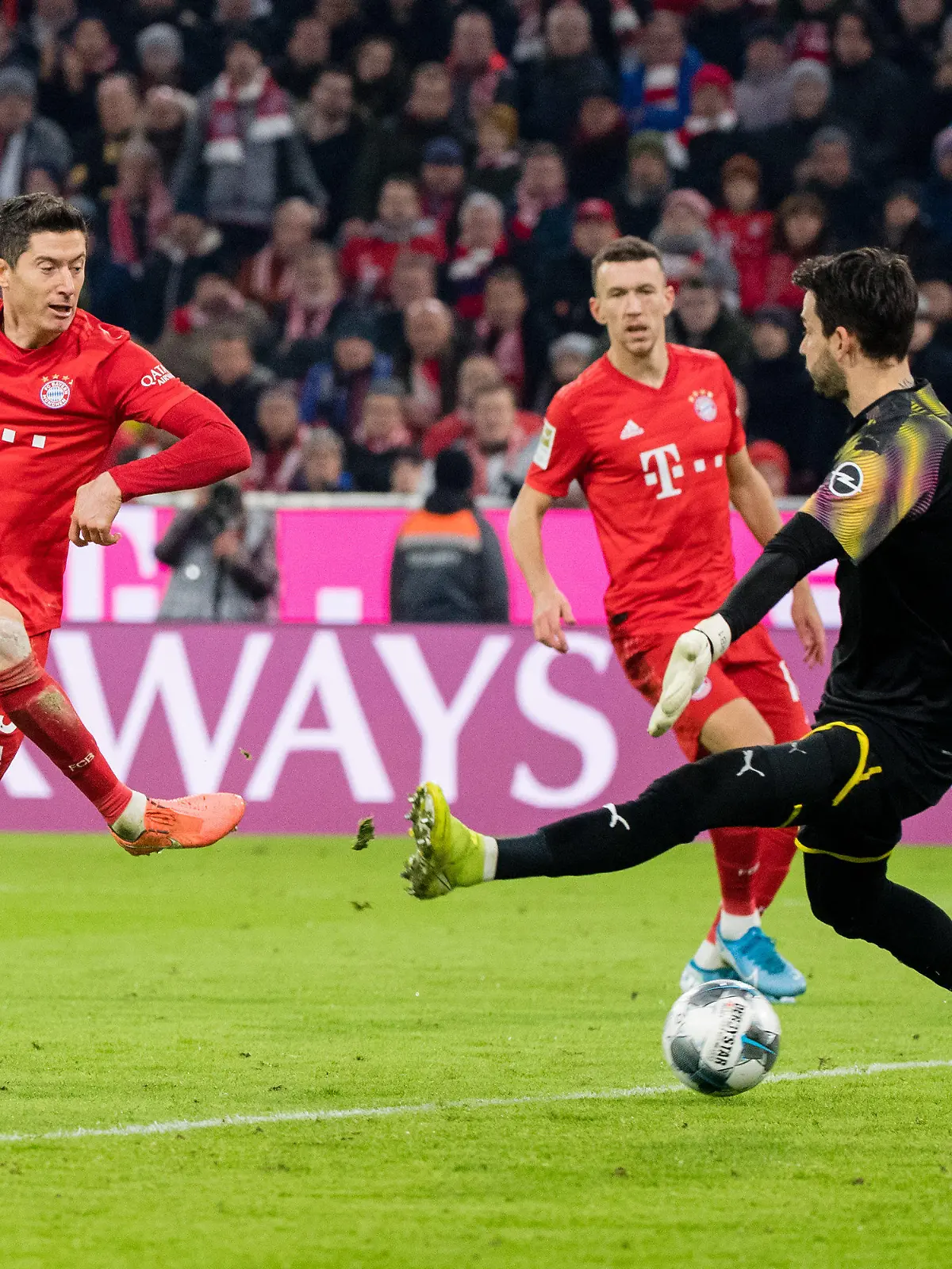ARCHIV - 09.11.2019, Bayern, München: Fußball: Bundesliga, Bayern München - Borussia Dortmund, 11. Spieltag in der Allianz Arena. Robert Lewandowski vom FC Bayern München (l) trifft zum 3;0. Rechts kann Torwart Roman Bürki von Dortmund den Ball nicht halten. In der Mitte läuft Ivan Perisic vom FC Bayern München. (zu dpa: «Flick traut Lewandowski Müllers 40-Tore-Marke zu: «Alles ist machbar»») Foto: Matthias Balk/dpa - WICHTIGER HINWEIS: Gemäß den Vorgaben der DFL Deutsche Fußball Liga bzw. des DFB Deutscher Fußball-Bund ist es untersagt, in dem Stadion und/oder vom Spiel angefertigte Fotoaufnahmen in Form von Sequenzbildern und/oder videoähnlichen Fotostrecken zu verwerten bzw. verwerten zu lassen. +++ dpa-Bildfunk +++