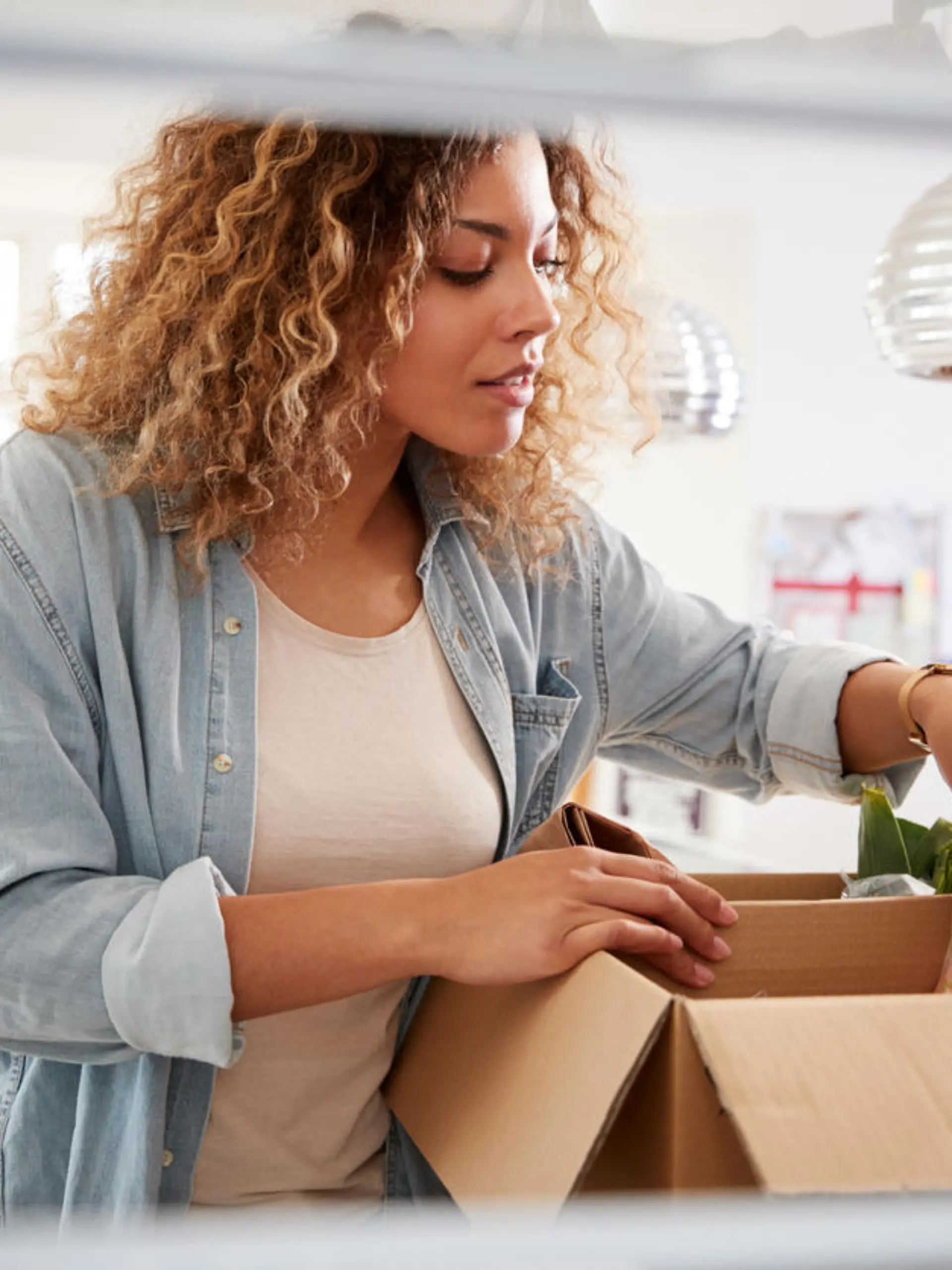 View Looking Out From Inside Of Refrigerator As Woman Unpacks Online Home Food Delivery