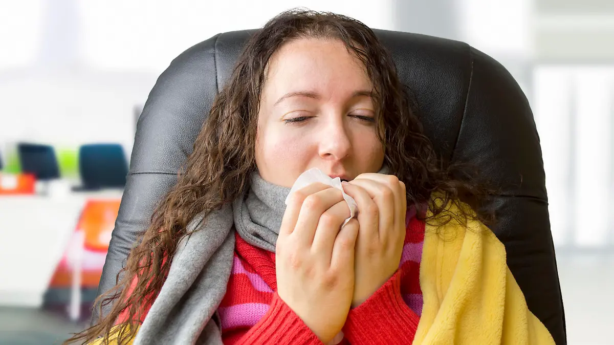 portrait of a woman with tissue sneezing at the office