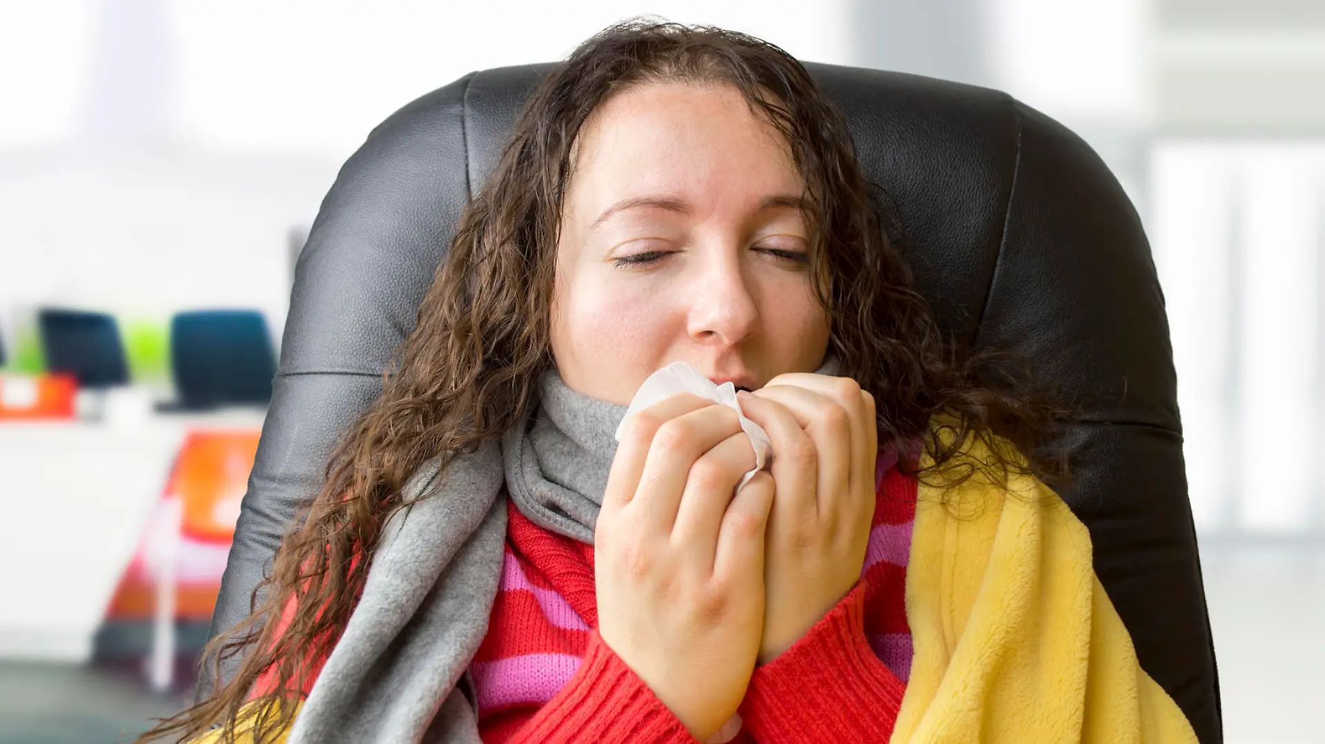 portrait of a woman with tissue sneezing at the office