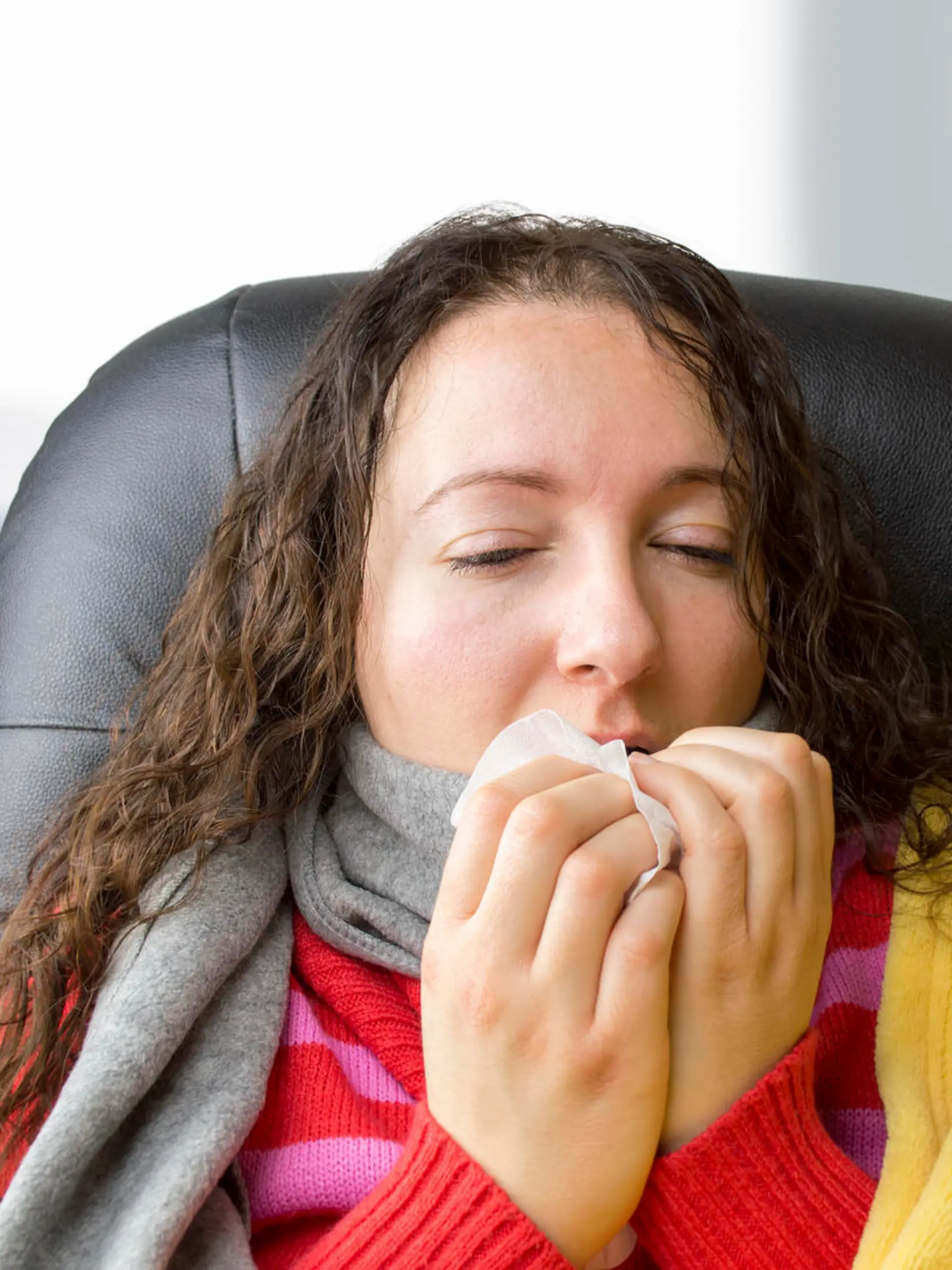 portrait of a woman with tissue sneezing at the office