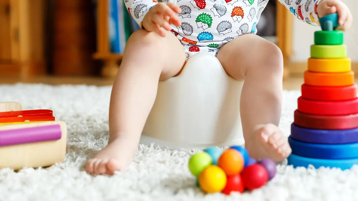Baby sitzt auf dem Töpfchen und spielt