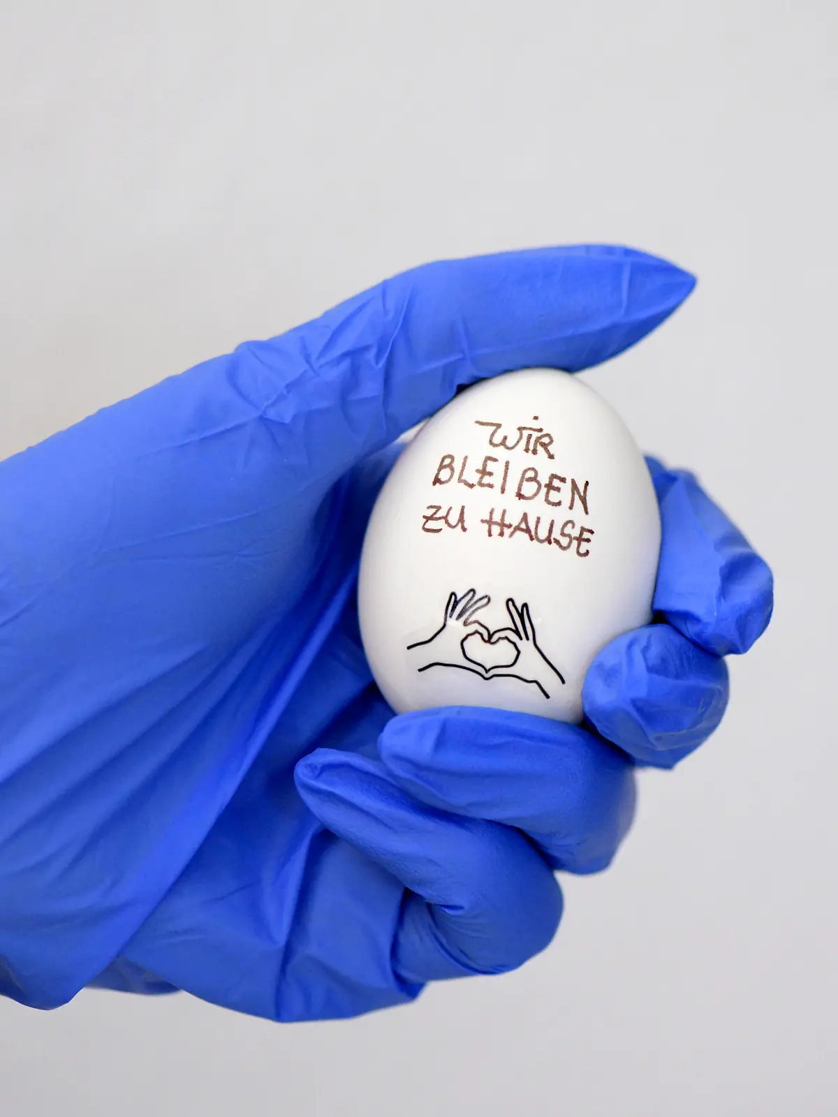 31.03.2020, Symbolbild: Ei und Gummihandschuhe: Wir bleiben zu Hause auf einem Hühnerei. Ein Slogan wegen der Ausgangsbeschränkung in Deutschland. 31.03.2020, Ei und Gummihandschuhe 31.03.2020, Ei und Gummihandschuhe *** 31 03 2020, Symbol picture egg and rubber gloves We stay at home on a hens egg A slogan because of the exit restriction in Germany 31 03 2020, egg and rubber gloves 31 03 2020, egg and rubber gloves 