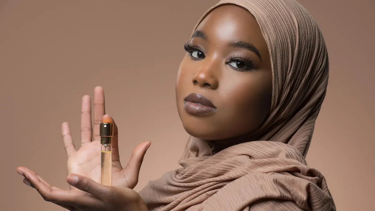 Beautiful Muslim Woman wearing hijab holding a perfume bottle