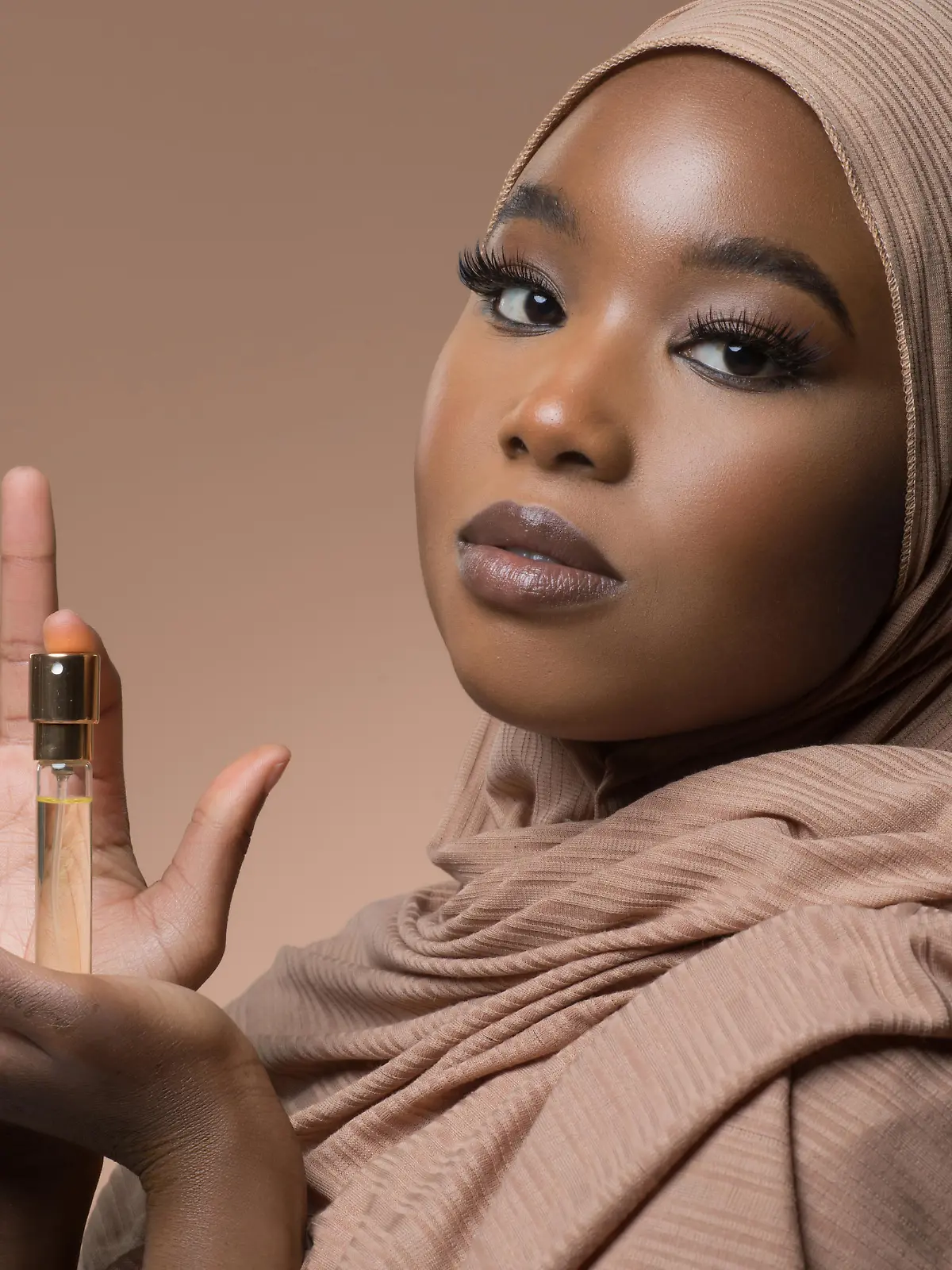 Beautiful Muslim Woman wearing hijab holding a perfume bottle