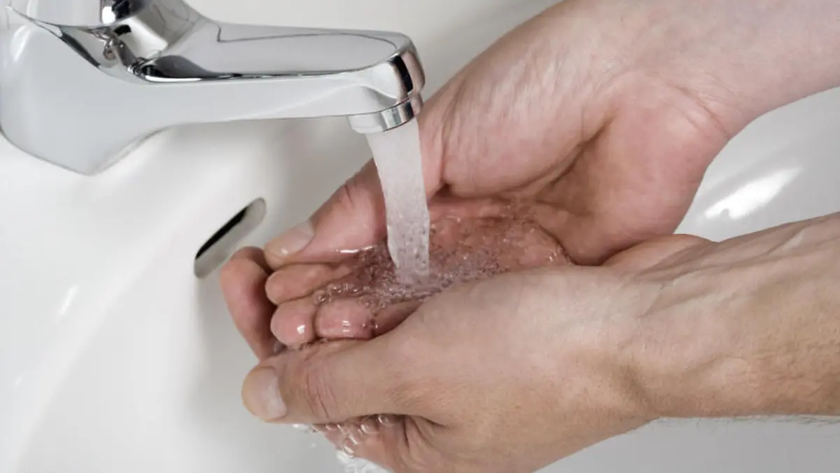 washing hands under flowing water from tap