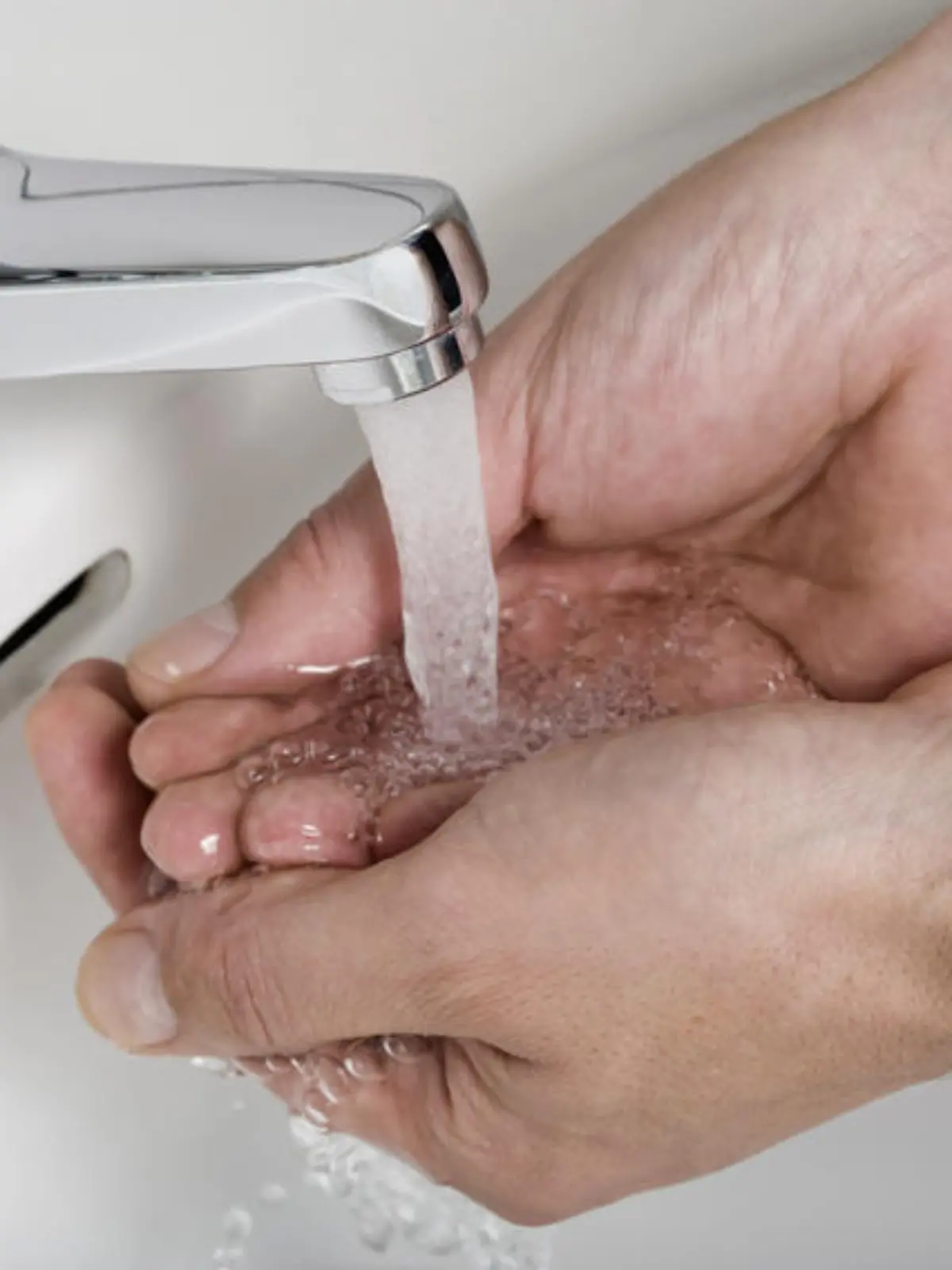 washing hands under flowing water from tap
