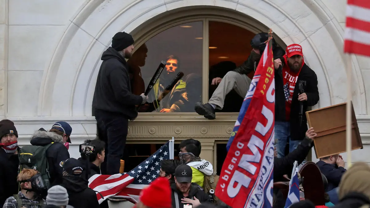 FILE PHOTO: A mob of supporters of then-U.S. President Donald Trump climb through a window they broke as they storm the U.S. Capitol Building in Washington, U.S., January 6, 2021. REUTERS/Leah Millis/File Photo