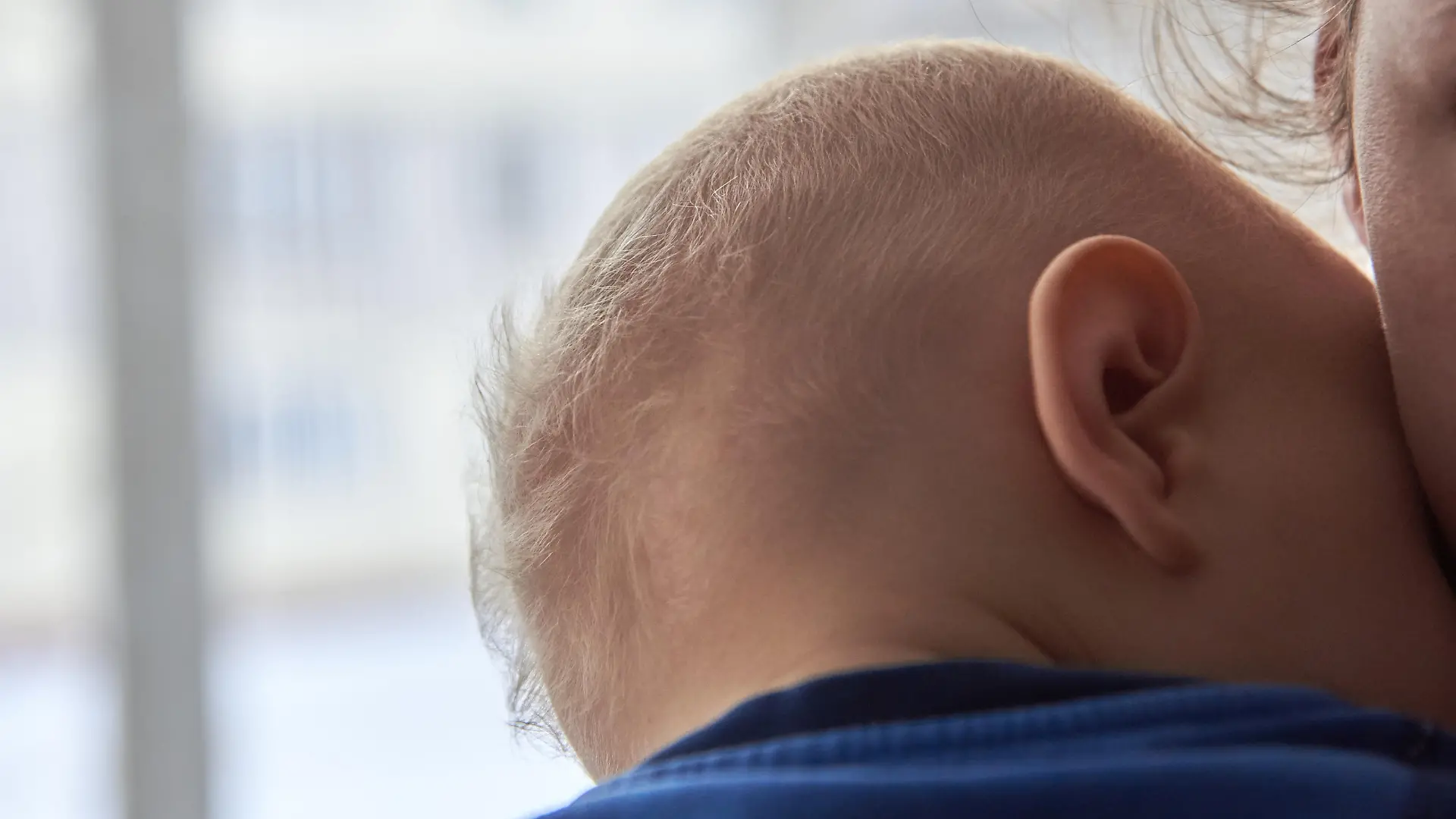 Mutter hält Baby mit dünnem Haar im Arm