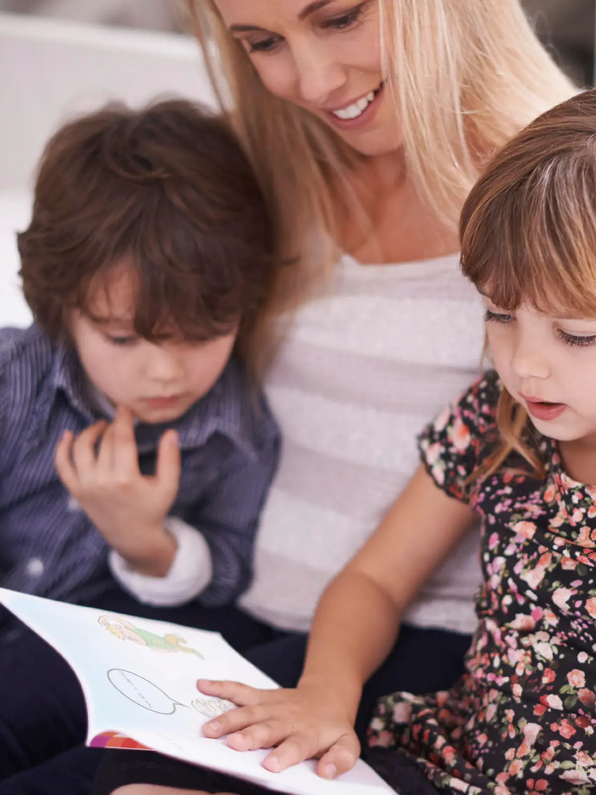 Shot of a mother reading with her children at home
