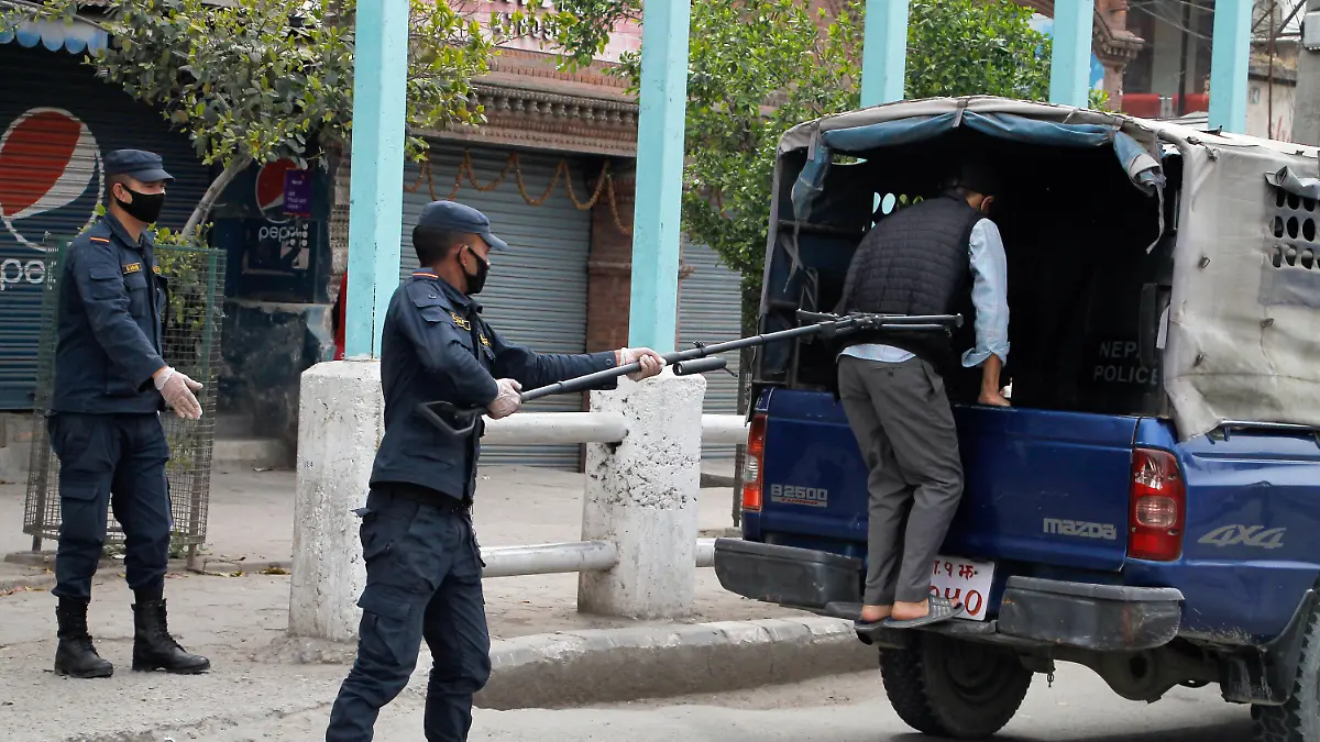 HANDOUT - 27.03.2020, Nepal, Kathmandu: Ein Polizist benutzt einen Abstandshalter, um einen Mann in ein Polizeifahrzeug zu schieben. Foto: Manoj Bhusan Khadka/Polizei Nepal/dpa - ACHTUNG: Nur zur redaktionellen Verwendung im Zusammenhang mit der aktuellen Berichterstattung und nur mit vollständiger Nennung des vorstehenden Credits +++ dpa-Bildfunk +++