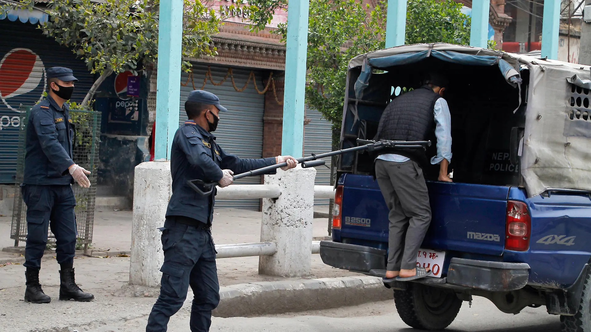 HANDOUT - 27.03.2020, Nepal, Kathmandu: Ein Polizist benutzt einen Abstandshalter, um einen Mann in ein Polizeifahrzeug zu schieben. Foto: Manoj Bhusan Khadka/Polizei Nepal/dpa - ACHTUNG: Nur zur redaktionellen Verwendung im Zusammenhang mit der aktuellen Berichterstattung und nur mit vollständiger Nennung des vorstehenden Credits +++ dpa-Bildfunk +++