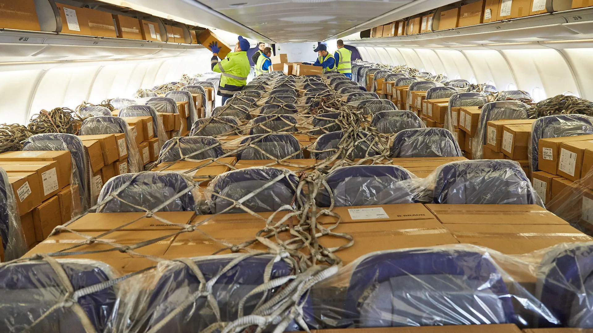 HANDOUT - 27.03.2020, Hessen, Frankfurt/Main: Der Logistikdienstleister DB Schenker und Lufthansa Cargo haben 2.780.000 Atemschutzmasken an die Landesregierung von Hessen geliefert. Die 12,7 Tonnen medizinisches Material erreichten aus Schanghai kommend den Frankfurter Flughafen. Um die rund 6.000 Kartons in dem Passagierflugzeug vom Typ A330 unterzubekommen, wurden auch die Sitzreihen in der Kabine sowie die Staufächer über den Sitzen bepackt. Foto: Deutsche Bahn AG/Lufthansa Cargo/dpa - ACHTUNG: Nur zur redaktionellen Verwendung im Zusammenhang mit der aktuellen Berichterstattung und nur mit vollständiger Nennung des vorstehenden Credits +++ dpa-Bildfunk +++