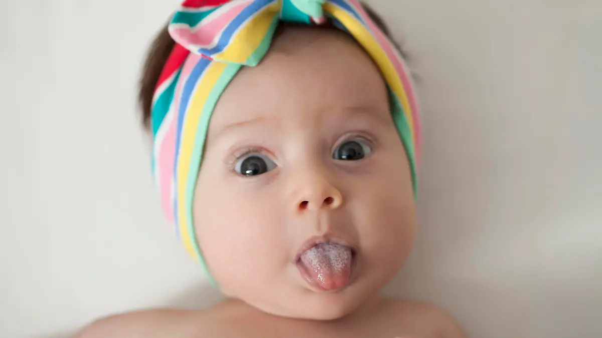 Verkürztes Zungenbändchen: Baby streckt die Zunge heraus.