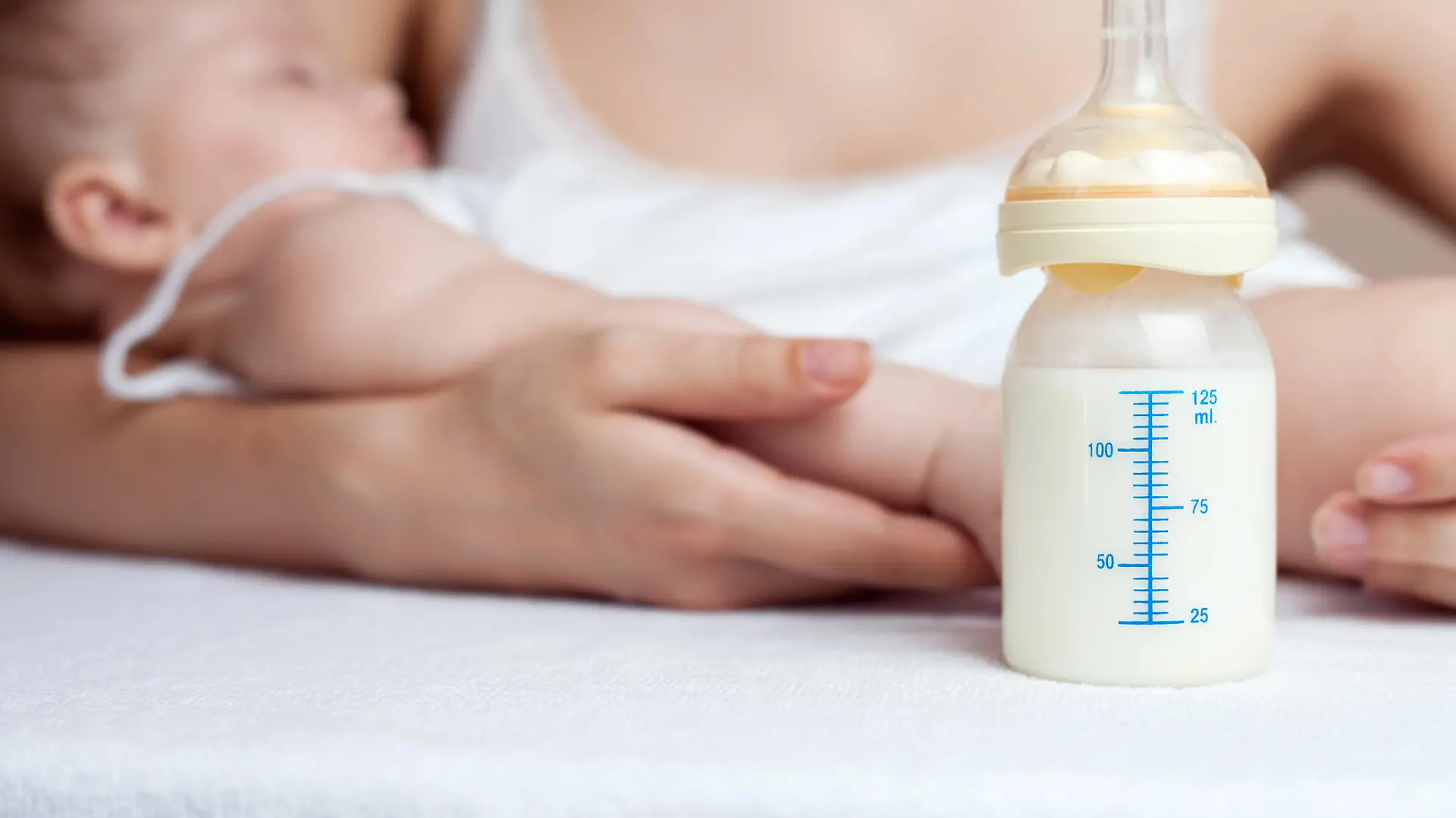 Brusternährungsset: Mutter mit Baby an der Brust und Milchfläschchen