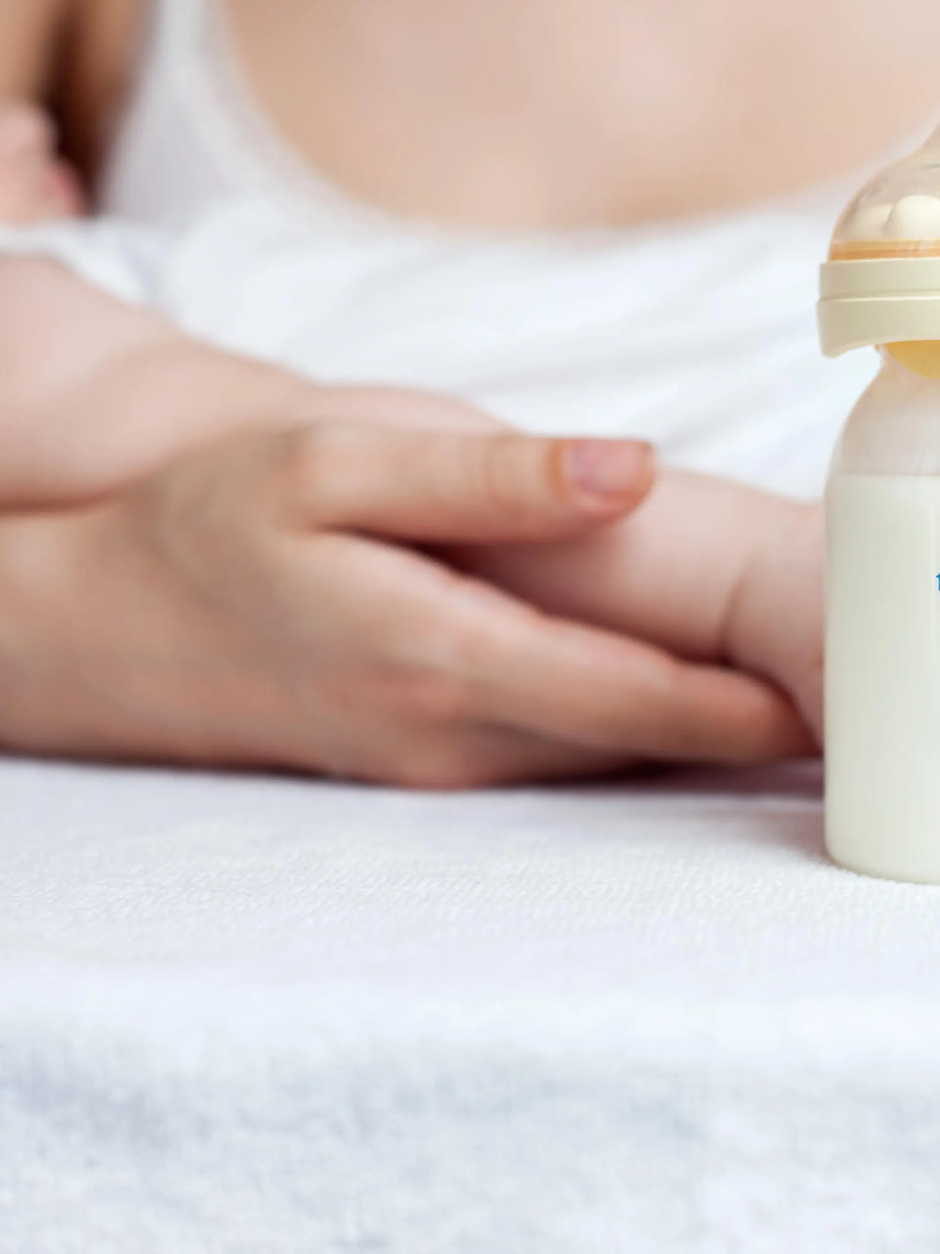 Brusternährungsset: Mutter mit Baby an der Brust und Milchfläschchen