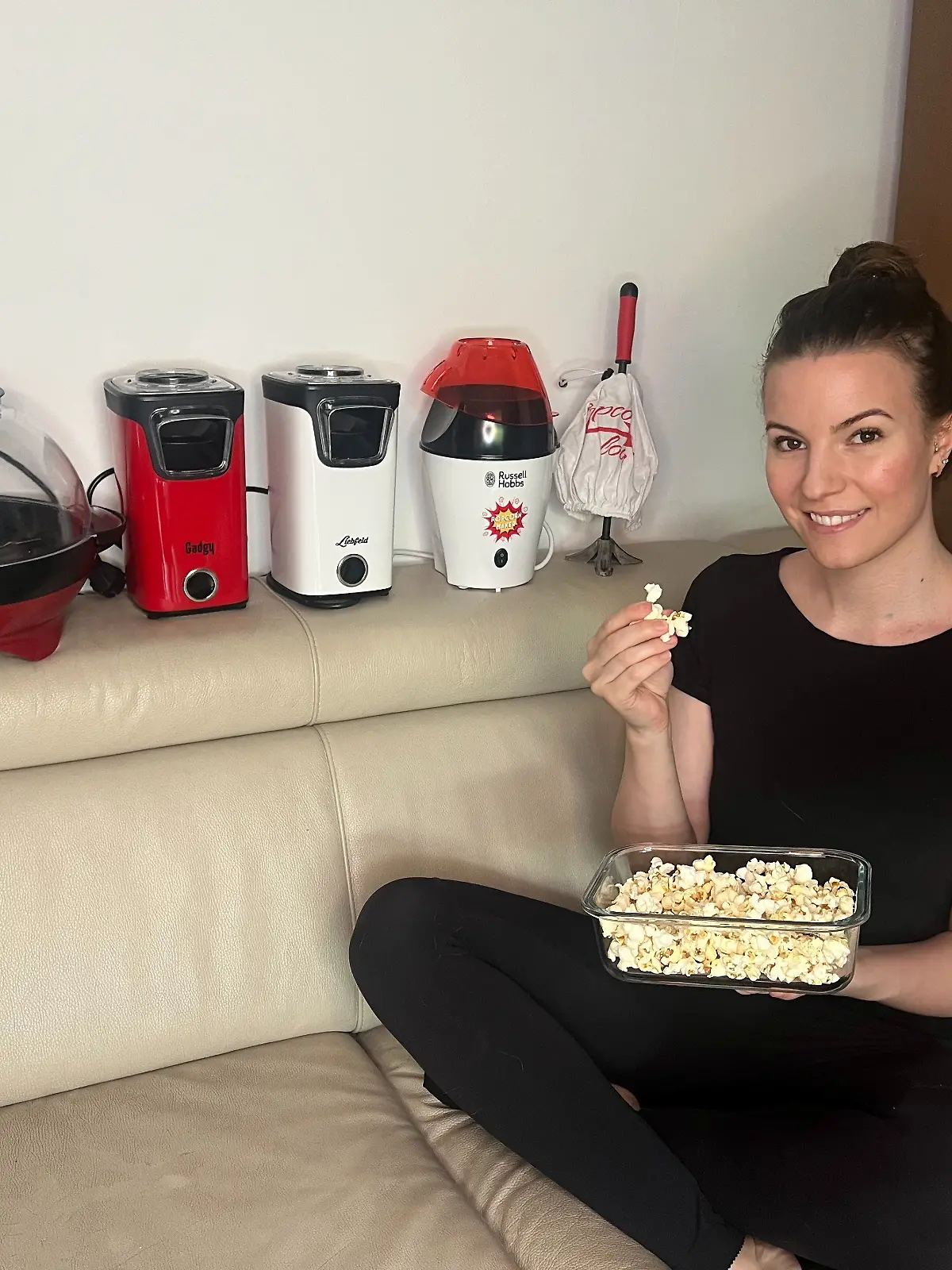 RTL-Reporterin Isabelle Kurz sitzt mit fünf Popcornmaschinen und einer Schüssel Popcorn auf der Couch. 