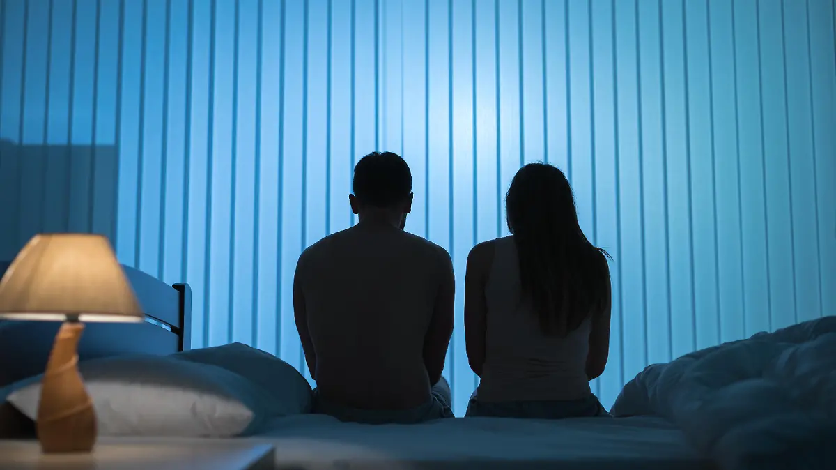 The man and woman sit on the bed. night time