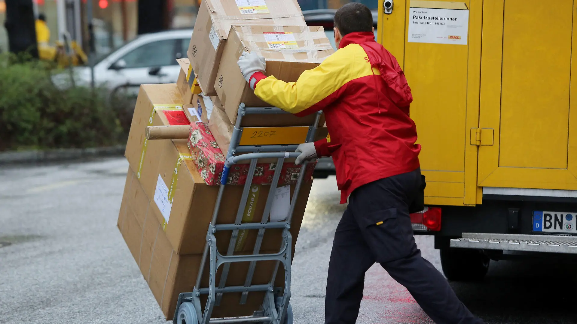 ARCHIV - 24.12.2014, Hamburg: Ein Paketbote von DHL liefert Päckchen aus. Wer in Deutschland ein Paket nach Hause bestellt, könnte dafür langfristig mehr bezahlen müssen. (zu dpa «Paketbranche erwägt Preisaufschlag für Haustür-Bestellungen») Foto: Malte Christians/dpa +++ dpa-Bildfunk +++