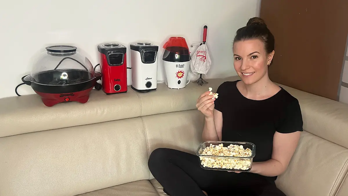 Isabelle Kurz sitzt mit fünf Popcornmaschinen und einer Schüssel Popcorn auf der Couch.