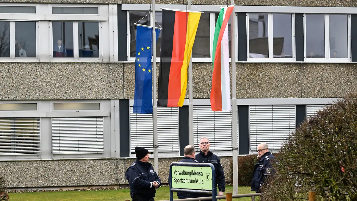 13.03.2023, Nordrhein-Westfalen, Freudenberg: Mitarbeiter des Ordnungsamtes stehen vor dem Schulzentrum des ermordeten Mädchens. Die Schule hat geöffnet, die Fahnen sind auf Halbmast geflaggt und die Schüler werden von Therapeuten begleitet. In einem Waldstück wurde gestern die Leiche eines 12jährigen Mädchens gefunden. Das Mädchen wurde am Samstag vermisst und die Polizei startete eine groß angelegte Suchaktion, bei der die Leiche am Sonntag entdeckt wurde. Foto: Roberto Pfeil/dpa - ACHTUNG: Person(en) wurde(n) aus rechtlichen Gründen gepixelt +++ dpa-Bildfunk +++