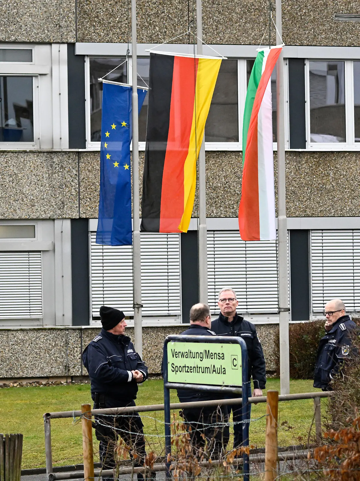13.03.2023, Nordrhein-Westfalen, Freudenberg: Mitarbeiter des Ordnungsamtes stehen vor dem Schulzentrum des ermordeten Mädchens. Die Schule hat geöffnet, die Fahnen sind auf Halbmast geflaggt und die Schüler werden von Therapeuten begleitet. In einem Waldstück wurde gestern die Leiche eines 12jährigen Mädchens gefunden. Das Mädchen wurde am Samstag vermisst und die Polizei startete eine groß angelegte Suchaktion, bei der die Leiche am Sonntag entdeckt wurde. Foto: Roberto Pfeil/dpa - ACHTUNG: Person(en) wurde(n) aus rechtlichen Gründen gepixelt +++ dpa-Bildfunk +++