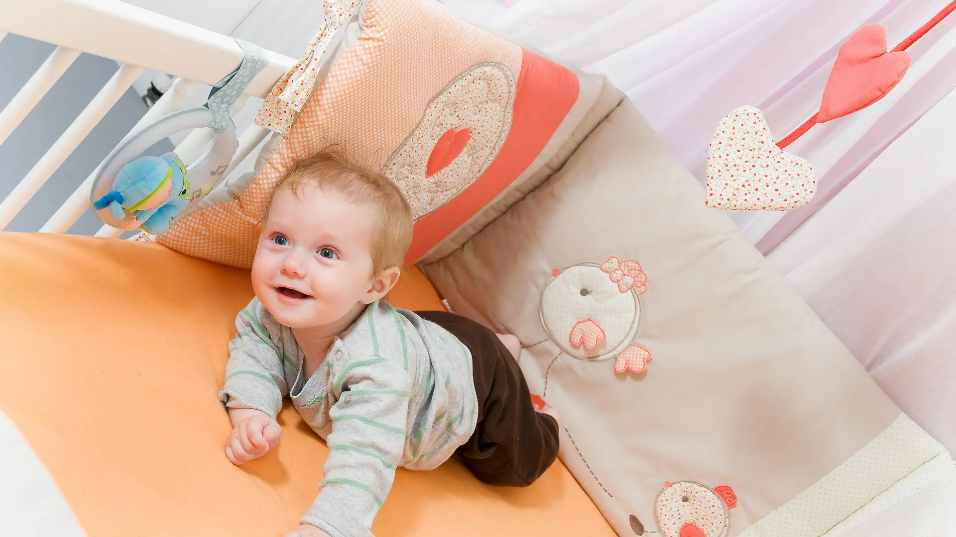 Baby liegt im Bettchen mit Bettgitter